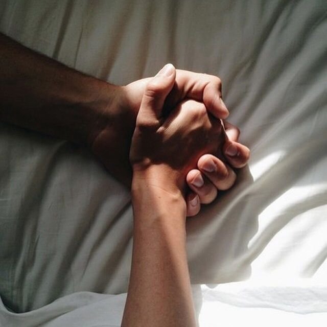 Two partners holding hands tightly on a bed, expressing intimacy and connection associated with Mutual Climax.
