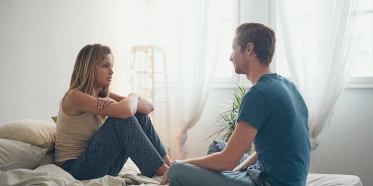 A couple sitting on a bed having an open conversation, supporting communication for Mutual Climax