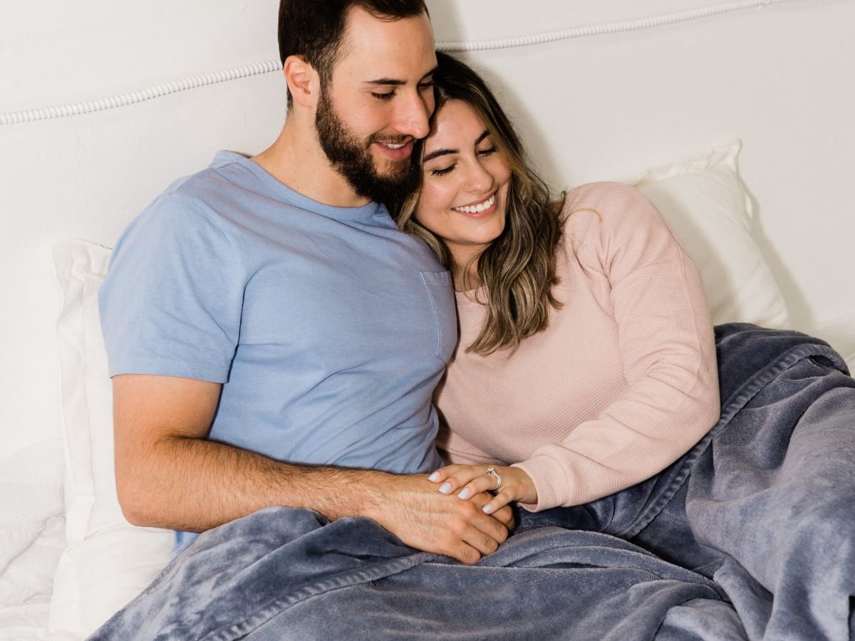 Happy couple cuddling under a blanket, sharing closeness that supports Mutual Climax