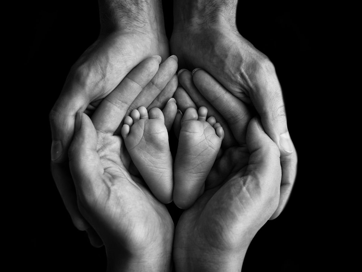 Parents holding newborn feet symbolizing intimacy, bonding, and Mutual Climax