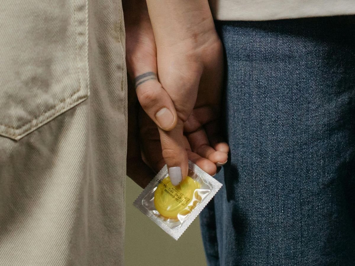 Couple holding hands discreetly with a condom, symbolizing shared readiness for Mutual Climax